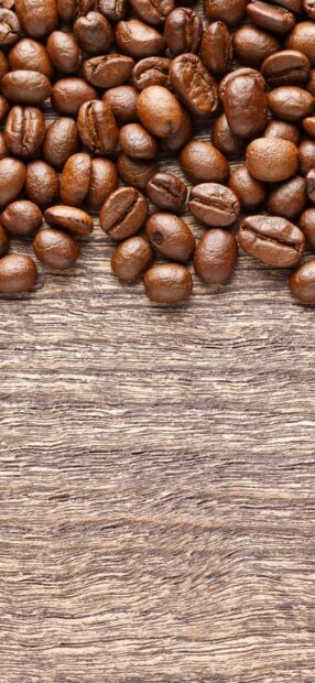 Close up of fresh coffee beans scattered on wooden surface with coffee beans
