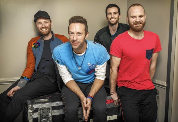The Coldplay band members posing together in a casual indoor setting