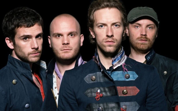 The Coldplay band members posing together in dark vintage jackets
