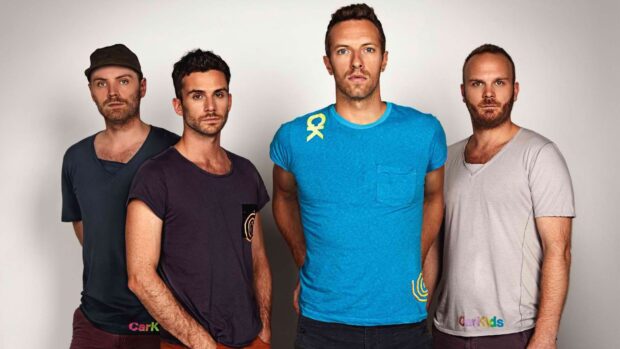 The four members of Coldplay standing in casual clothes against a plain background
