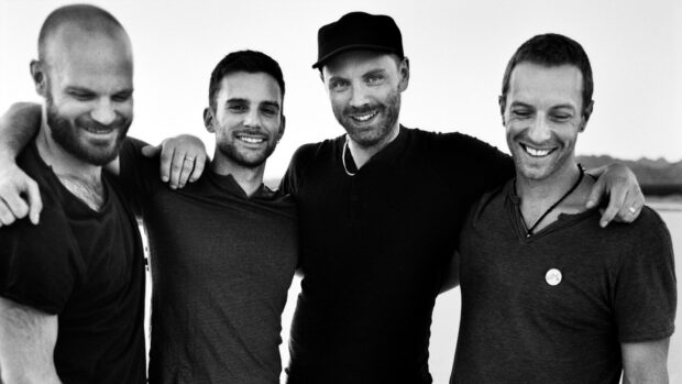 Coldplay members smiling together in a black and white photo with close friendship