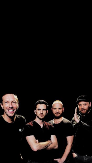 Coldplay band members standing together with black background in a confident pose
