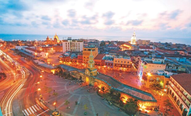 The historic clock tower and vibrant cityscape in Colombia at dusk with busy streets and illuminated buildings