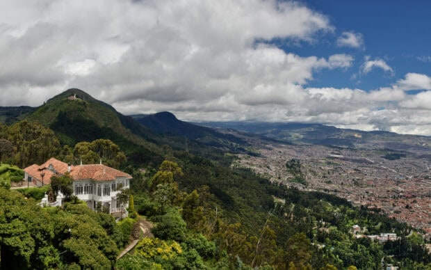 A scenic view of Colombia hills and a white colonial house surrounded by lush greenery