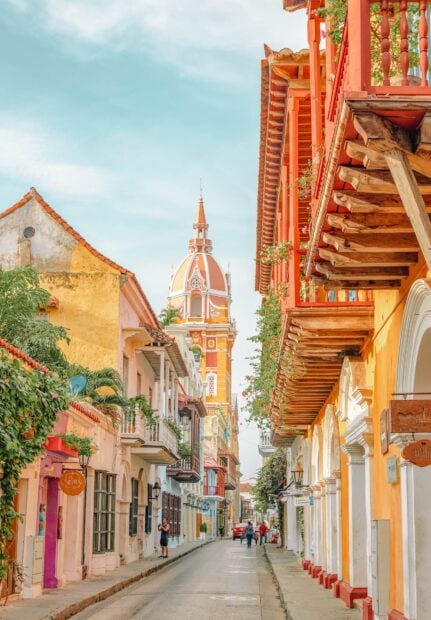 Colorful colonial street architecture in Colombia cityscape with tower and people walking