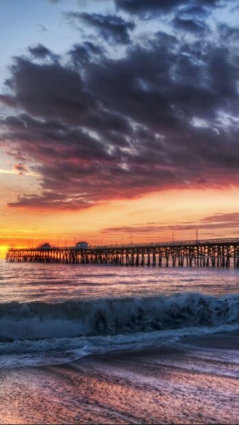 Stunning Colombia coastline with a wooden pier and colorful sunset clouds over the ocean waves