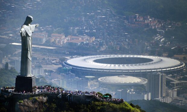 A large crowd gathered near the Corcovado Mountain statue overlooking the cityscape and stadium
