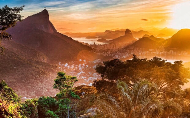 View of Corcovado Mountain with lush forest and cityscape at sunset in Rio de Janeiro