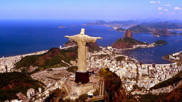 A panoramic view of Corcovado Mountain with the statue overlooking the cityscape and ocean