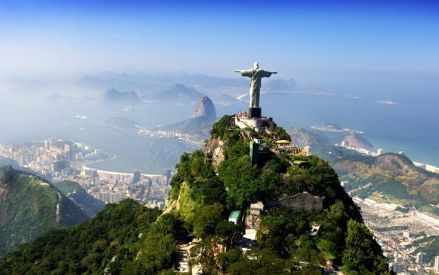 A scenic view of Corcovado Mountain with lush greenery and the famous statue overlooking the city and bay