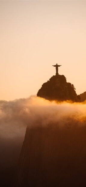 Corcovado Mountain at sunset with mist surrounding the peak and statue on top