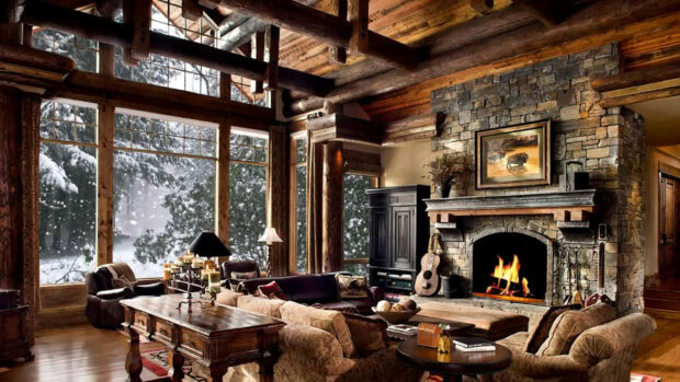 A cozy winter cabin interior with wooden beams and stone fireplace surrounded by snowy trees