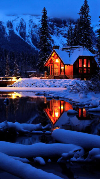 Snow covered cabin reflecting on the lake in a winter mountain setting