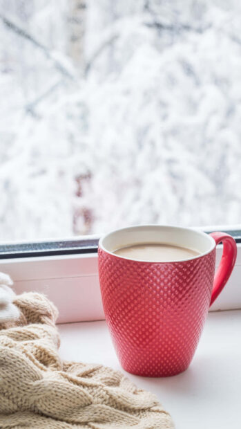 Warm knitwear with a hot drink near window during cozy winter