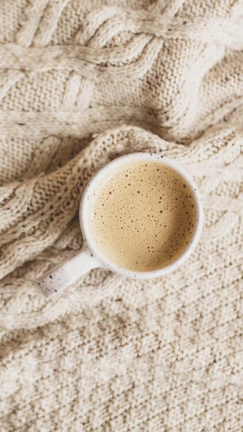 A cozy cup of coffee on a knitted sweater during winter comfort