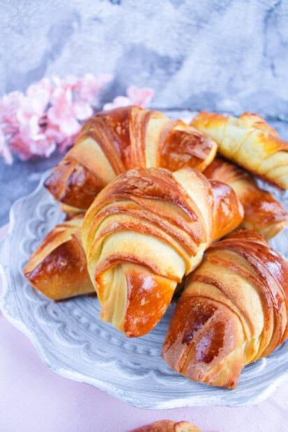 Freshly baked croissant with golden brown layers on a decorative plate