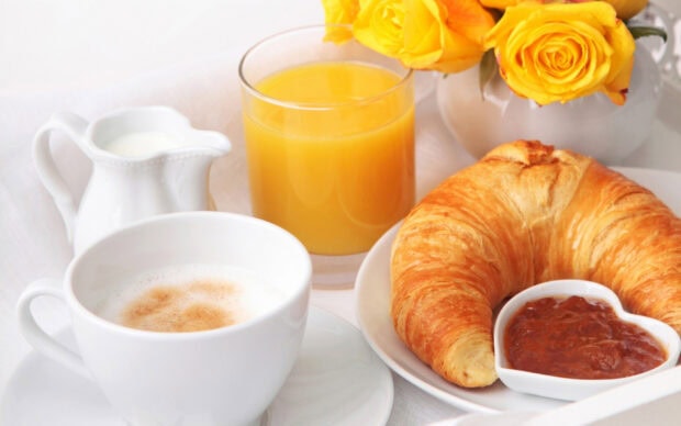 A fresh croissant served with jam and coffee for a delightful breakfast setting