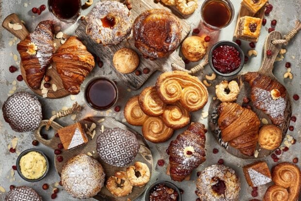 A variety of croissant and pastries served with jam and coffee on a rustic table