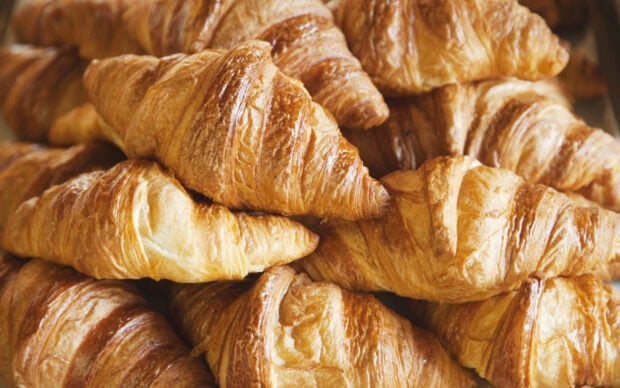 Fresh croissant stacked together showing the flaky golden layers and crispy texture