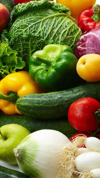 Fresh cucumber surrounded by various fresh vegetables and fruits in vibrant colors