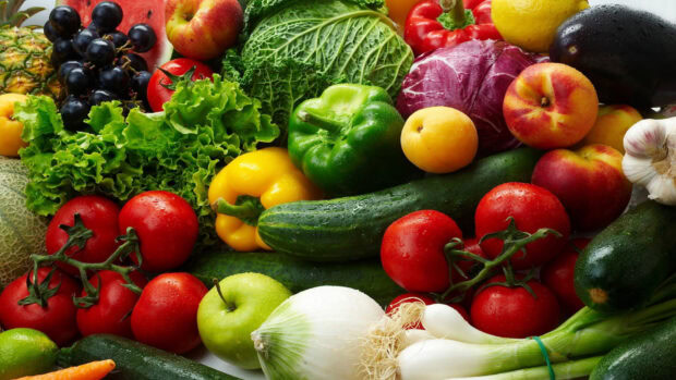 Fresh cucumber surrounded by various vegetables and fruits in vibrant colors