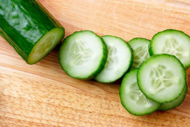 Fresh cucumber slices arranged on a wooden cutting board