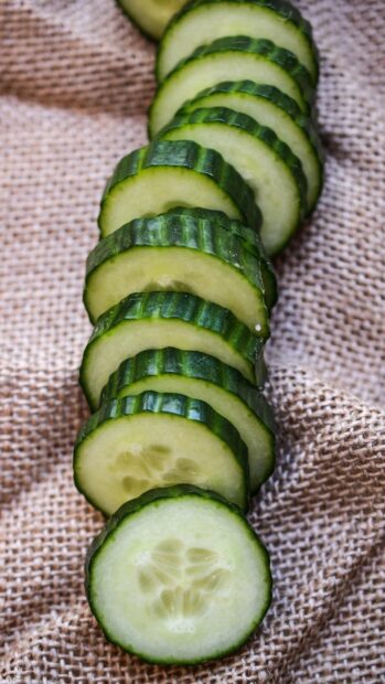 Fresh cucumber slices arranged neatly on a textured fabric surface