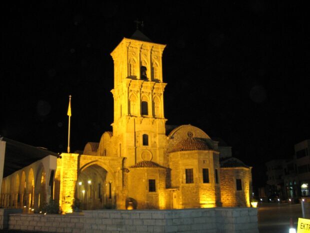 A historic Cyprus church tower illuminated at night with detailed stone architecture