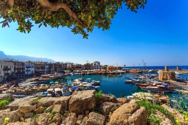 A picturesque Cyprus harbor with boats stone walls and clear blue sky in the background