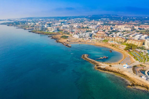 Aerial view of a coastal city in Cyprus with clear turquoise waters and beachfront resorts