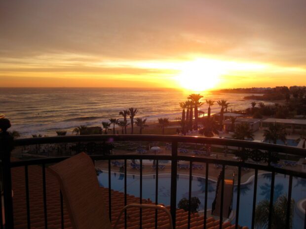 A beautiful Cyprus sunset over the sea and palm trees viewed from a balcony