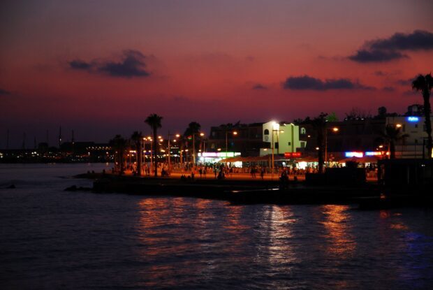 Evening cityscape in Cyprus with illuminated streets and palm trees by the water