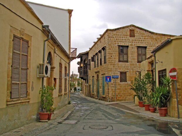 Old stone buildings and narrow street in Cyprus town with potted plants