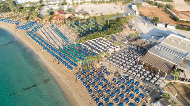 Aerial view of Cyprus beach with colorful umbrellas and sun loungers on the sand