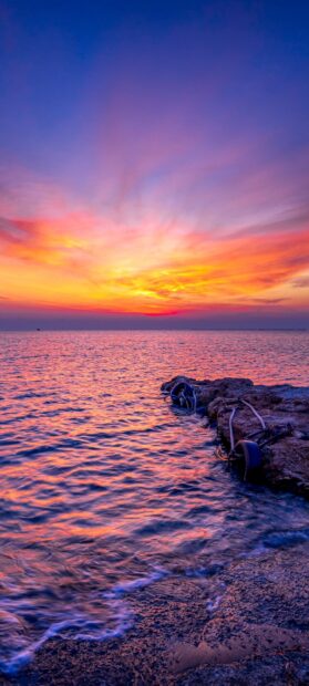 Vibrant Cyprus sunset over the sea with colorful sky and rocky shore at dusk