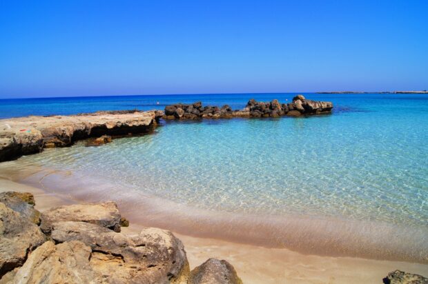 Clear Cyprus coastline with rocks and crystal blue water on a sunny day