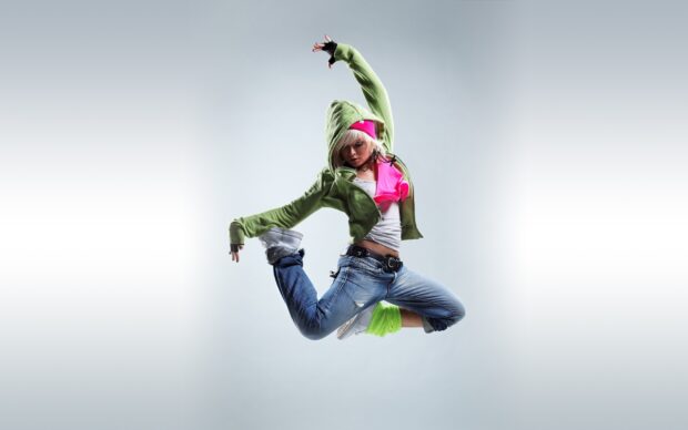 A dancer performing a dynamic jump wearing casual streetwear and bright accessories