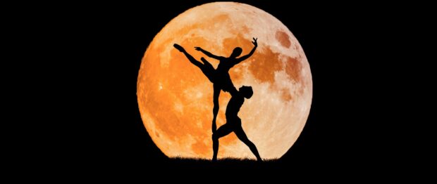 Silhouette of dancer performing a lift in front of a large orange full moon