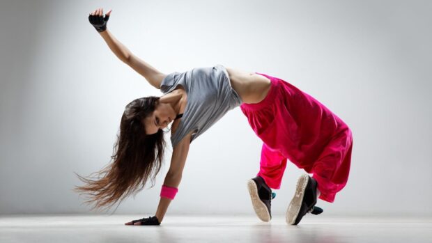 A dancer performing a dynamic breakdance move in casual clothing with vibrant pink pants