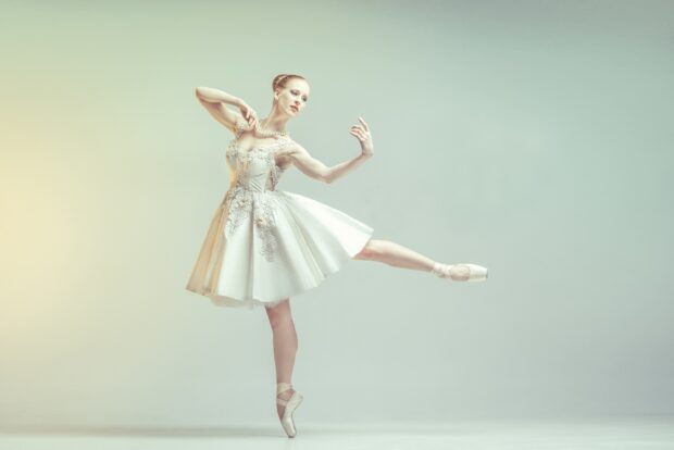 Elegant ballerina dancer performing a graceful pose in a white dress