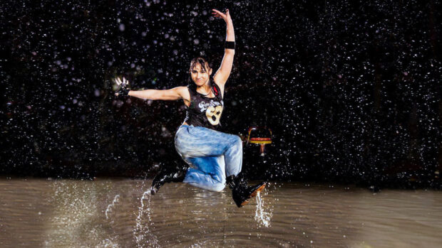 Female dancer jumping in water with vibrant dance moves at night