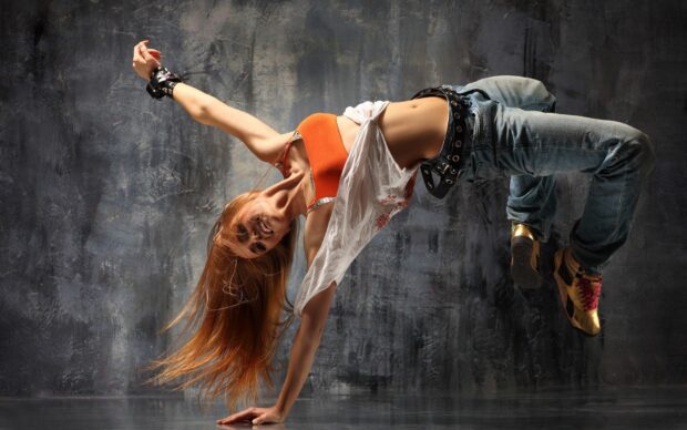 Female dancer wearing casual clothes performing a one hand breakdance move