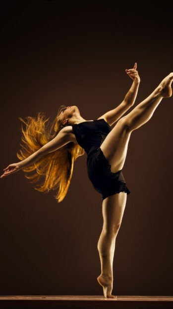 A dancer performing an elegant high kick with flowing hair and strong posture