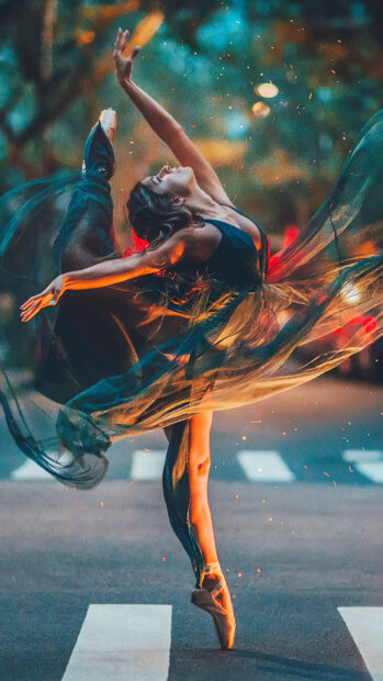A graceful dancer performing an arabesque pose in a flowing dress on the street at sunset