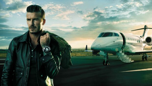 David Beckham standing near private jet with a bag over his shoulder