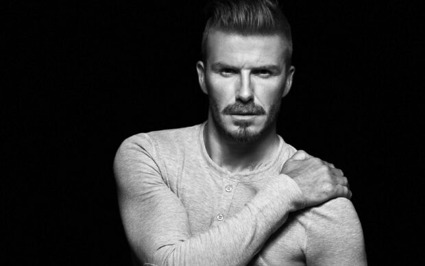 David Beckham wearing a long sleeve shirt with a serious expression and hand on shoulder