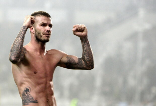 David Beckham celebrating with raised fists showing tattoos on arms