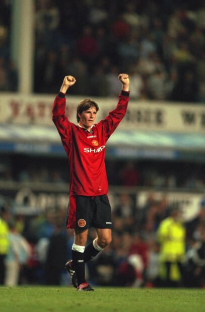 Young David Beckham celebrating a victory on the football field with raised arms
