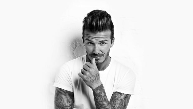 David Beckham posing with tattoos in a white shirt and styled hair