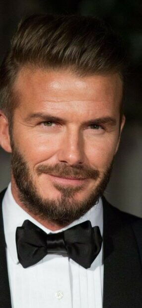 David Beckham dressed in a tuxedo with a black bow tie and a confident smile